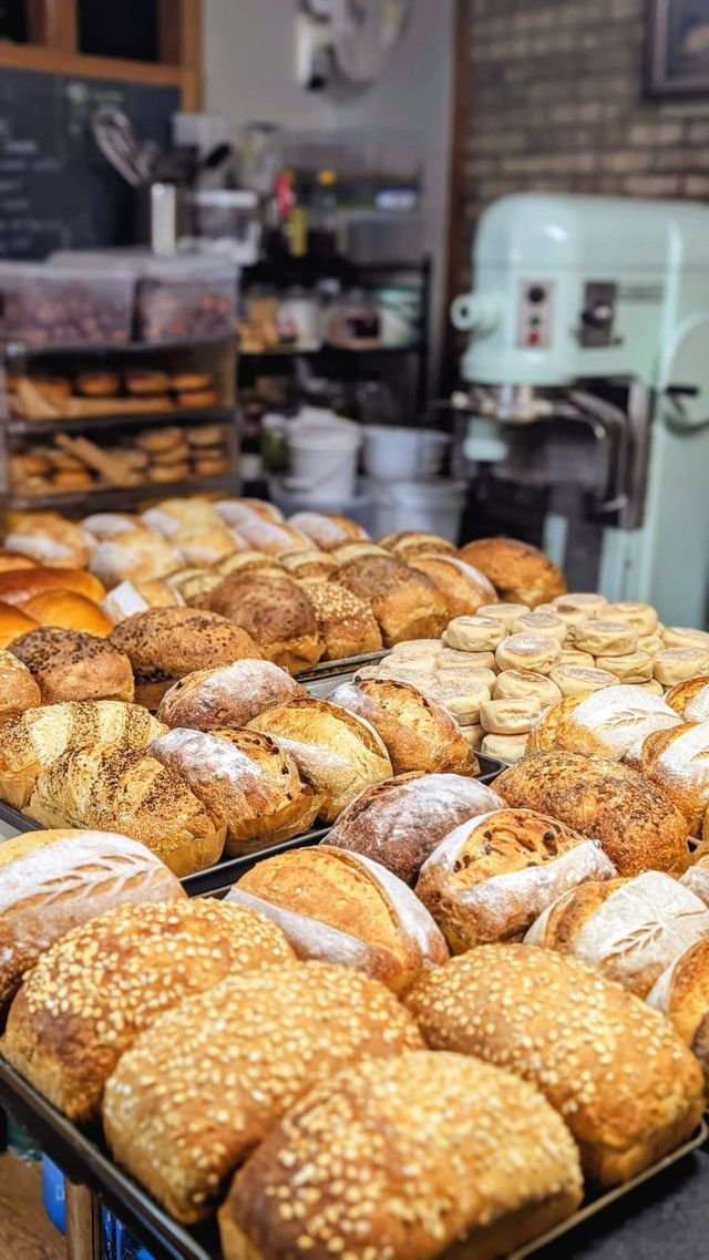 Trays of fresh loaves and rounds in front of a large mint-green mixer